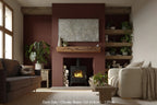 A dark oak fireplace beam installed on a red wall, supporting a mantel, with a cozy living room setting including a lit fireplace, couch, and armchair.