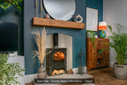 A dark oak fireplace beam positioned above a fireplace in a room with blue walls, wooden flooring, and various decorative items.