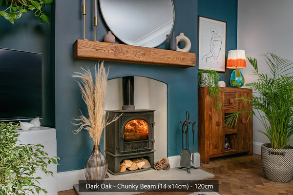 A dark oak fireplace beam positioned above a fireplace in a room with blue walls, wooden flooring, and various decorative items.