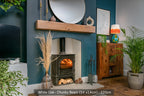 A white oak fireplace beam mounted on a blue wall above a fireplace, with decorative items and a wooden cabinet to the right.