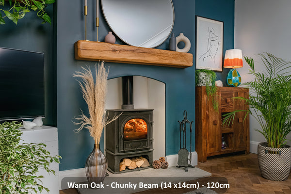 A rustic warm oak fireplace beam mounted on a blue wall above a fireplace, with decorative items and a potted plant in the room.