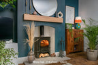 A contemporary clean lined white oak fireplace beam installed above a fireplace in a room with blue walls, wooden flooring, and various decorations.